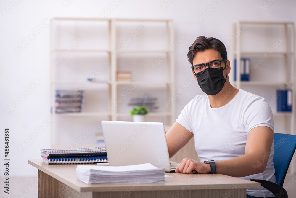Young male student employee working at workplace during pandemic