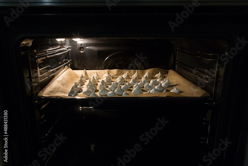 Meringue is baked on a baking sheet covered with parchment paper in the oven
