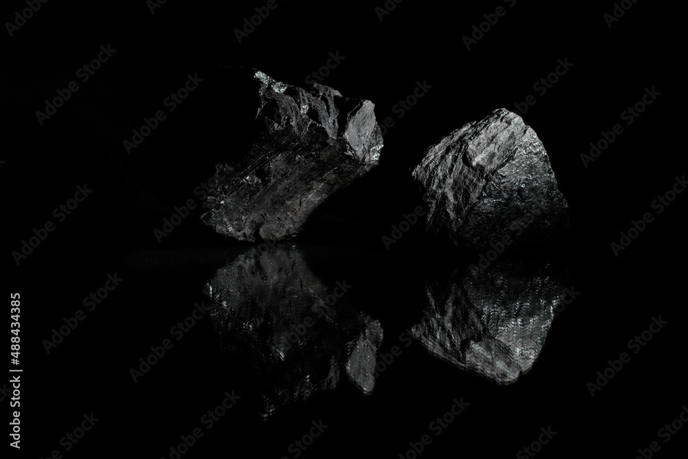 Coals are reflected in the glass surface. Stylish   photo for computer desktops and mobile home screens. Black rocks on a dark background. A wallpaper.