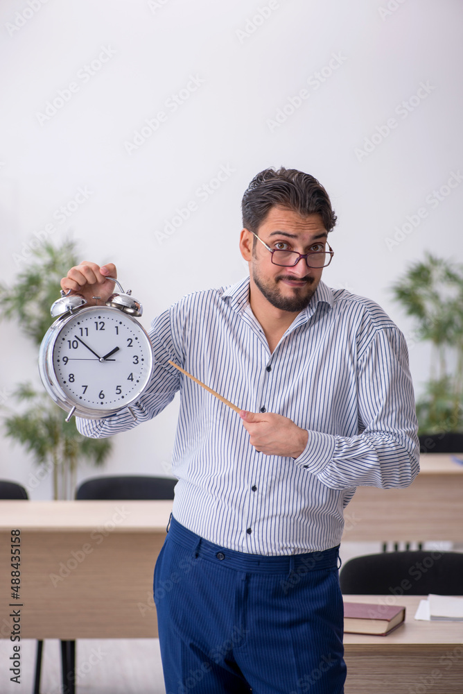 Young male teacher in time management concept Young male teacher in time management concept