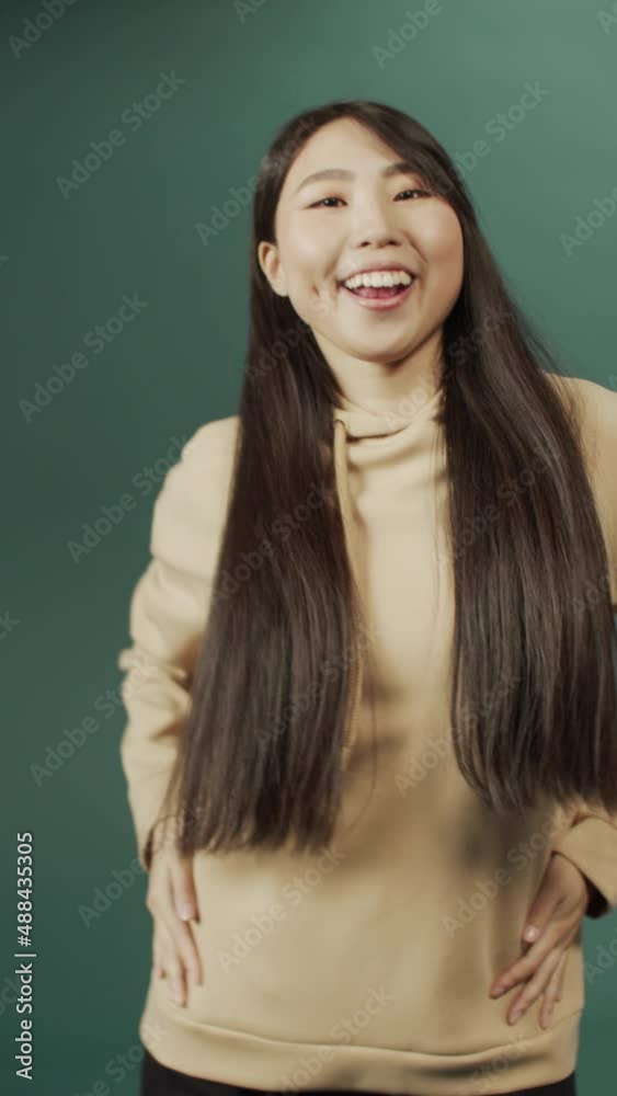 Young beautiful Chinese sporty woman wearing beige sweatshirt show popular dance moves Young beautiful Chinese sporty woman wearing beige sweatshirt show popular dance moves