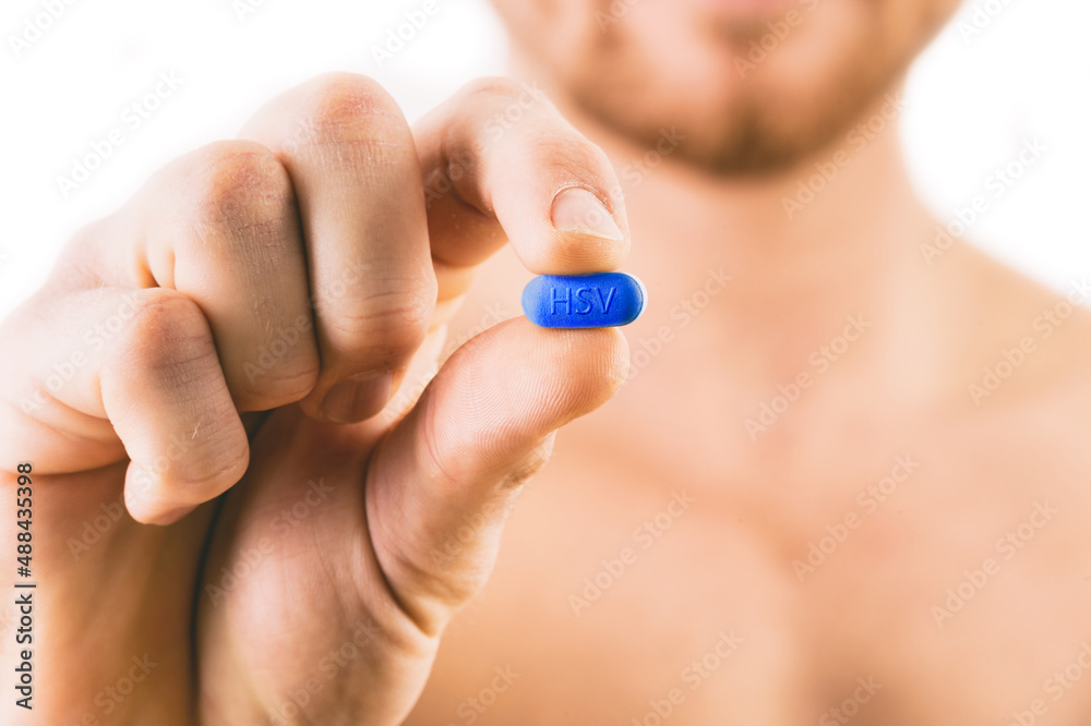 Muscular young man holding Herpes pill isolated on white background. Muscular young man holding Herpes pill isolated on white background.