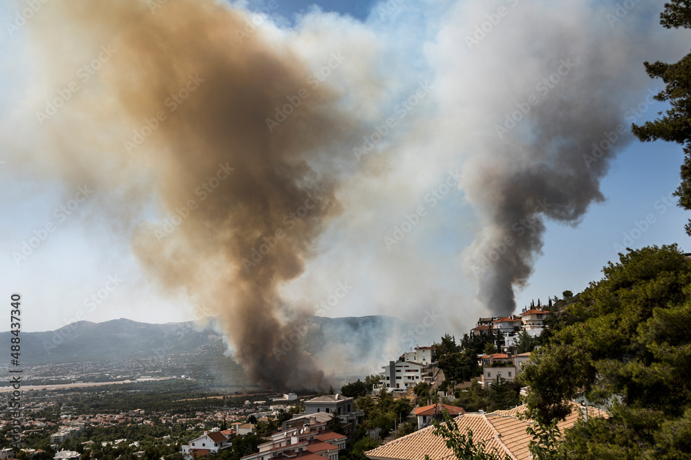 Athens, Greece, 03 August 2021: View of a major wild fire reached residential areas, at Varympompi suburb north of Athens. The thick smoke shows the  phenomenon of  pyrocumulus. 