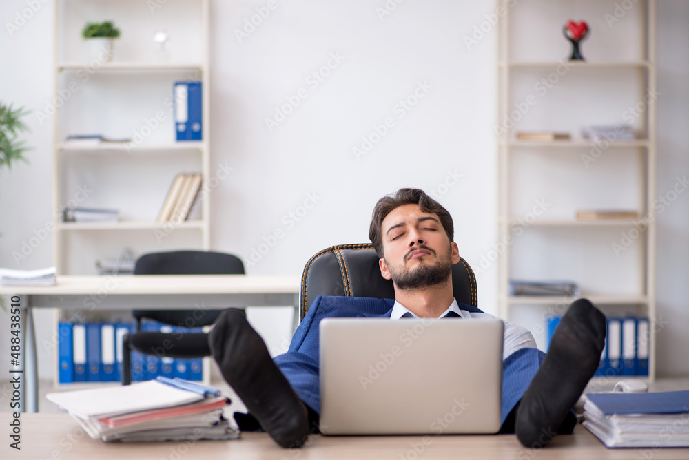 Young male employee extremely tired in the office Young male employee extremely tired in the office