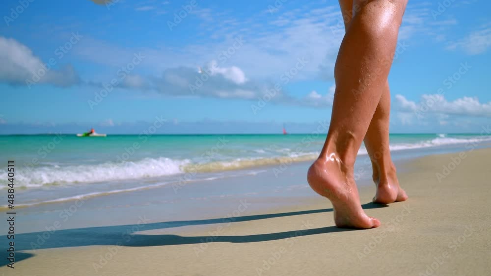 women's feet walk along the sandy beach to the shore of the blue sea. women's feet walk along the sandy beach to the shore of the blue sea.