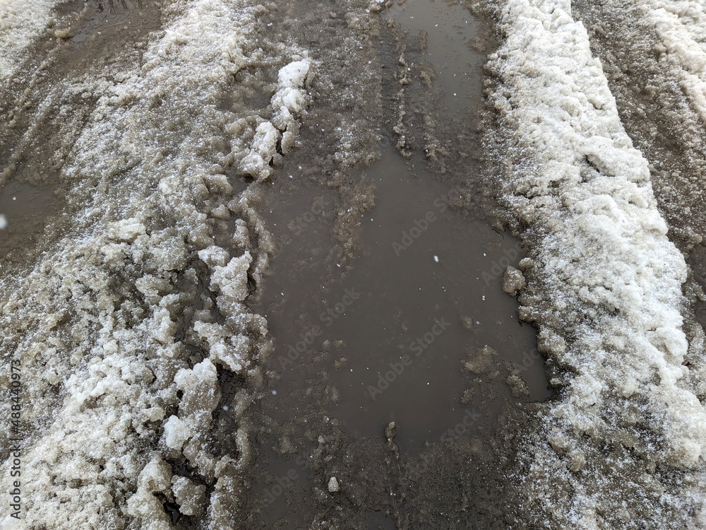 Fototapeta premium melted dirty snow on city streets photo in the daytime.