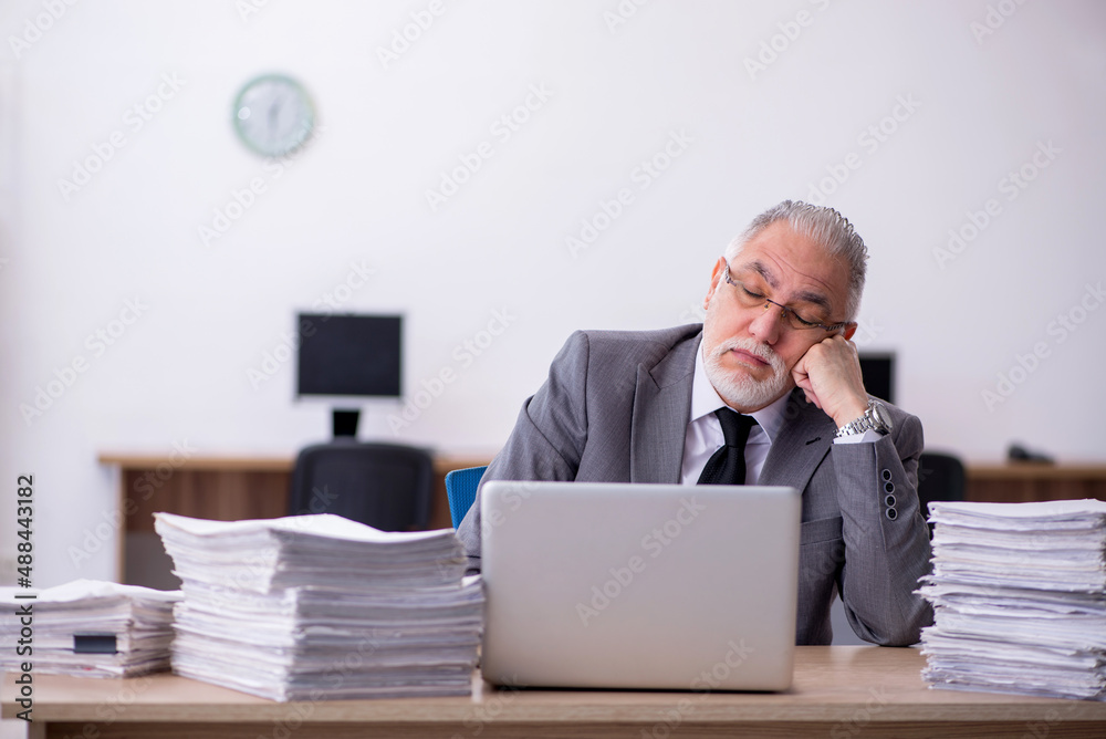 Old male employee unhappy with excessive work in the office Old male employee unhappy with excessive work in the office