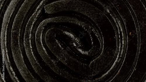 Extreme macro view with rotation of a licorice gummy candy spiral shaped. Dark chewy sweets. Candy texture pattern close up. photo