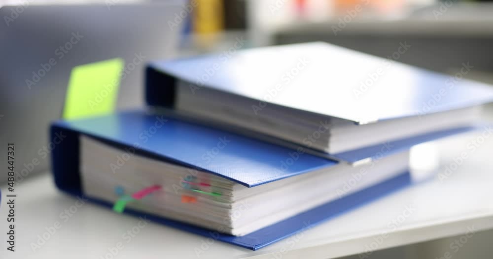 Stack of reporting paper documents in blue folder bookmarks on desktop in office Stack of reporting paper documents in blue folder bookmarks on desktop in office