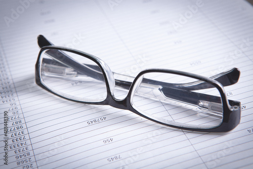 glasses with pen close up and financial report - accounting concept