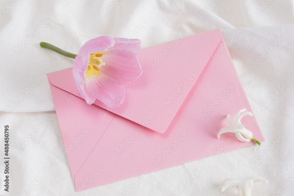 pink tulip and little white hyacinth flower and pink envelope on white bed linen, gift card, flower for anyone pink tulip and little white hyacinth flower and pink envelope on white bed linen, gift card, flower for anyone