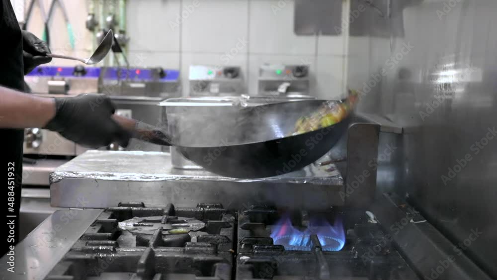 Slow motion of Chef Cookin wokg in the Kitchen. Restaurant wok fire cooking Close up, cook frying vegetable in the commercial kitchen. High quality FullHD footage Slow motion of Chef Cookin wokg in the Kitchen. Restaurant wok fire cooking Close up, cook frying vegetable in the commercial kitchen. High quality FullHD footage