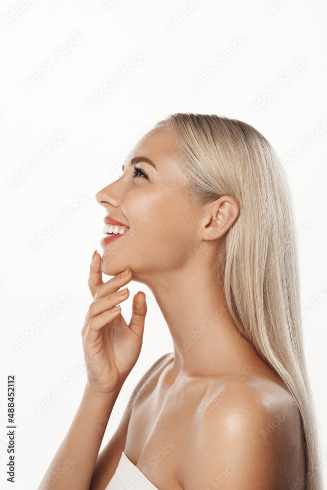 Skin care and women beauty. Vertical shot of blond woman standing in profile, using cleansing gel, skincare facial cream on fresh glowing skin, posing over white background Skin care and women beauty. Vertical shot of blond woman standing in profile, using cleansing gel, skincare facial cream on fresh glowing skin, posing over white background