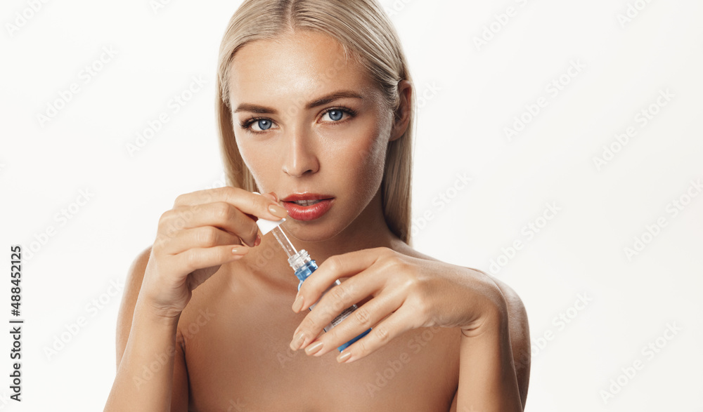 Skin care. Young woman apply moisturizing facial serum, hand holding dropper with essential oil, isolated on white background. Skincare and rejuvenation concept Skin care. Young woman apply moisturizing facial serum, hand holding dropper with essential oil, isolated on white background. Skincare and rejuvenation concept