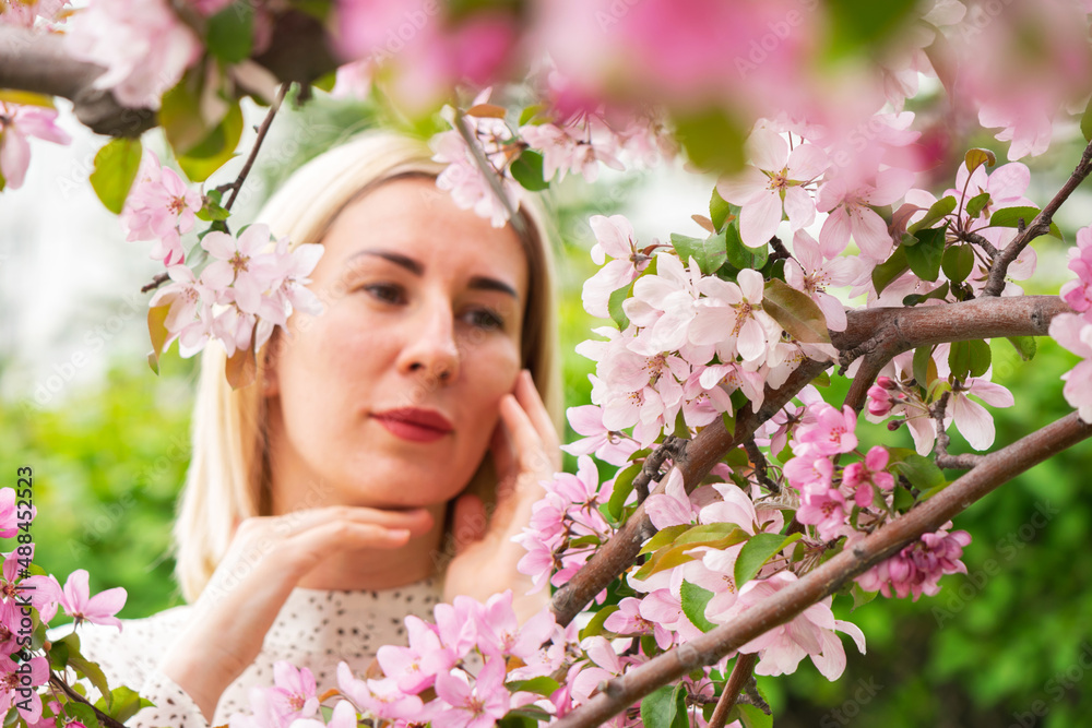 Young woman among the blossoming trees. Spring nature park or garden, flowering trees. Concept spring woman health