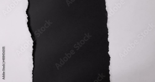 A paper is torn from the bottom up over a black background.