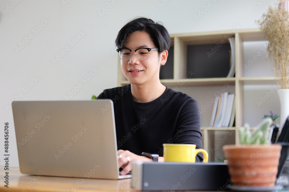 Smiling asian male working with laptop computer at creative office. Smiling asian male working with laptop computer at creative office.