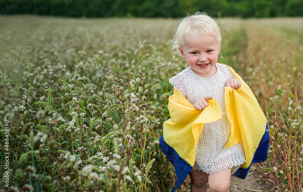 flag of Ukraine in the hands of a Ukrainian girl. A happy smiling child in a field runs along a rural road. Day of Defenders and Defenders of Ukraine flag of Ukraine in the hands of a Ukrainian girl. A happy smiling child in a field runs along a rural road. Day of Defenders and Defenders of Ukraine