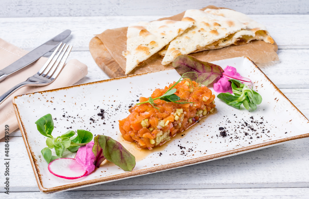 salmon Tartar on a plate on white wooden table salmon Tartar on a plate on white wooden table