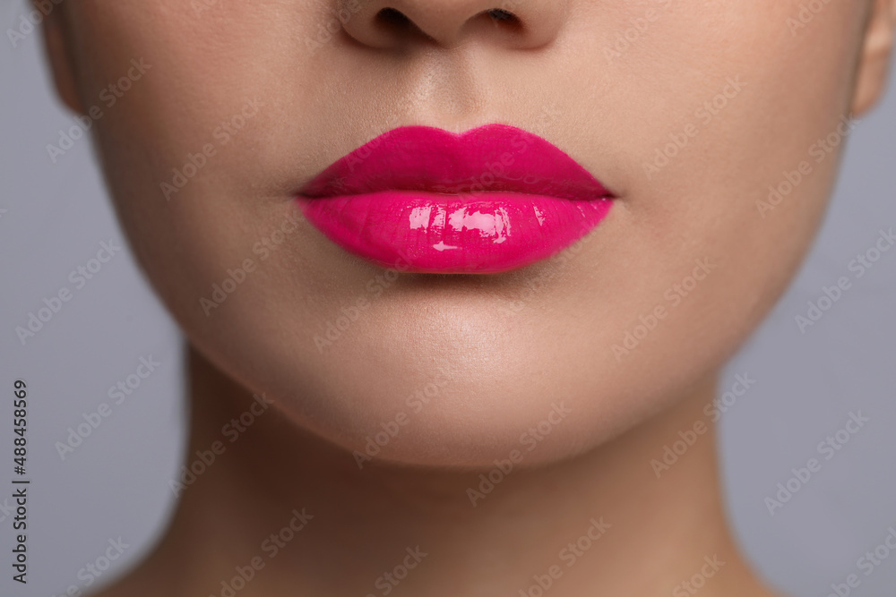 Closeup view of woman with beautiful full lips on grey background Closeup view of woman with beautiful full lips on grey background