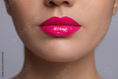 Closeup view of woman with beautiful full lips on grey background