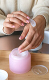 A woman spreads a white cream on her hand with a special spoon, close-up, vertical orientation, no face