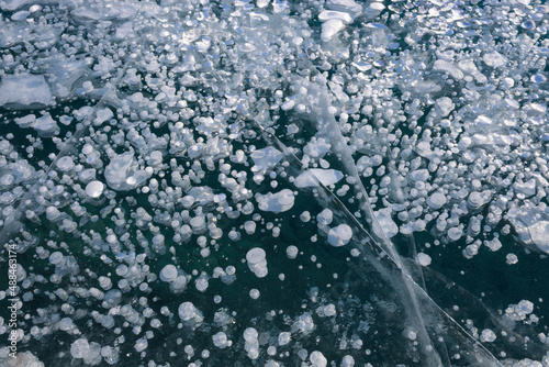 tiny frozen methane gas bubbles trapped under ice with fracture lines in Abraham Lake Alberta