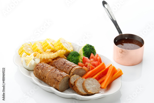 Chicken galantine, sliced, served on white plate with bbq sauce and vegetables. Selective focus photo