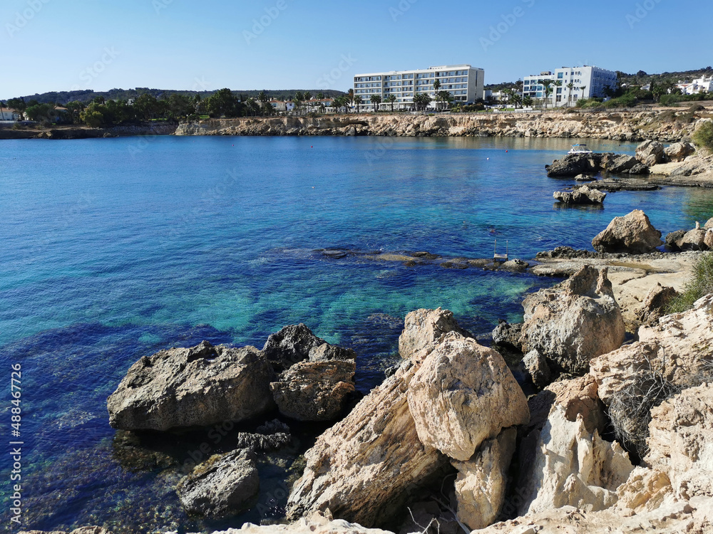 The rocky coast of the Mediterranean Sea with small bays, some of which are suitable for swimming people. There are hotels above the cliff.