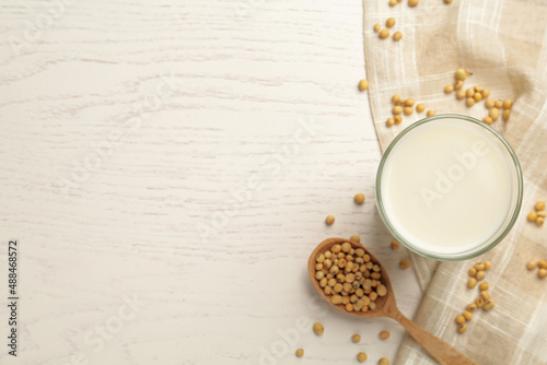 Glass with fresh soy milk and grains on white wooden table, flat lay. Space for text