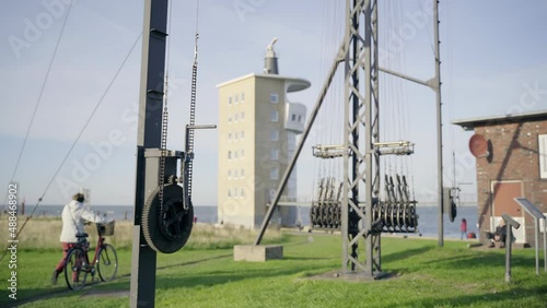 Passengers walking on a path alongside the northsea and a weather station photo