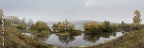 panorama of fog over the river with relief bushes in the foreground at dawn in autumn