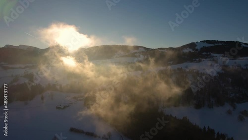 The sun hits the beautiful morning fog in the Alps during wintertime, filmed in 5k photo