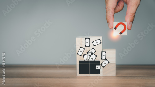 Obraz na plátně Hand put wooden cubes block with a big magnet to attract money