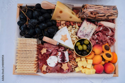 Delicious homemade festive snacks. Cheese Charcuterie Platter Board. Mixtures of cheese variety, mixed nuts, fruits, pickled olives. Great for party and family gatherings.