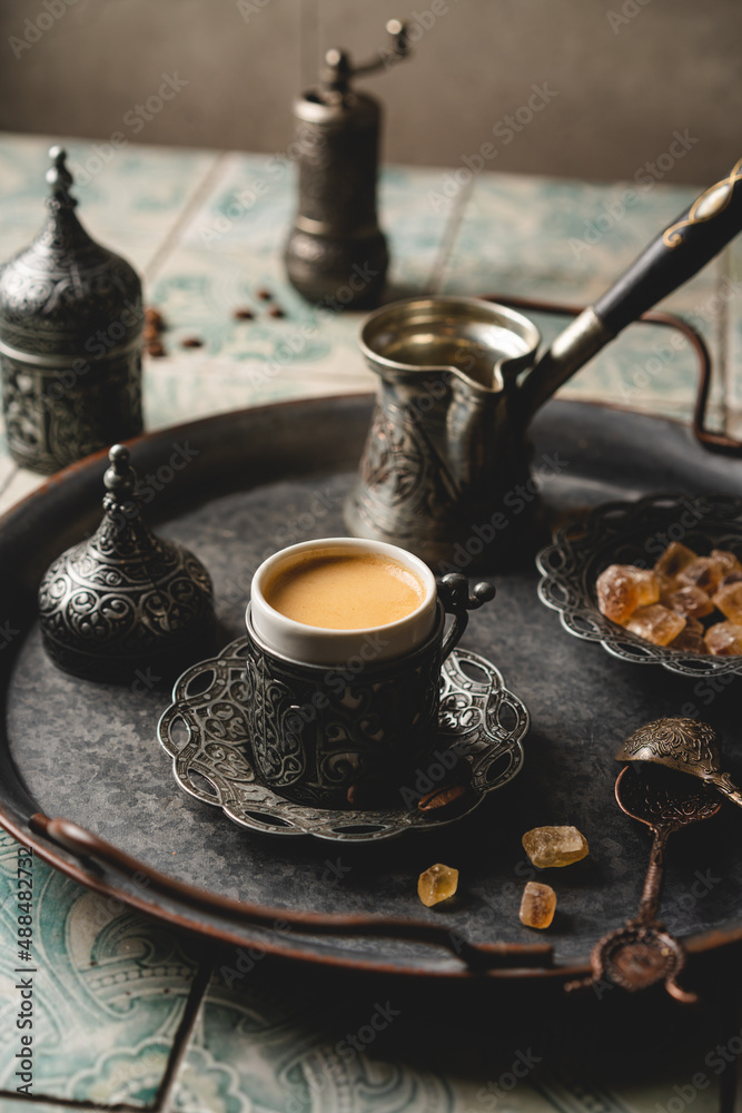 Coffee in metal Turkish traditional cup and coffee beans on tile background