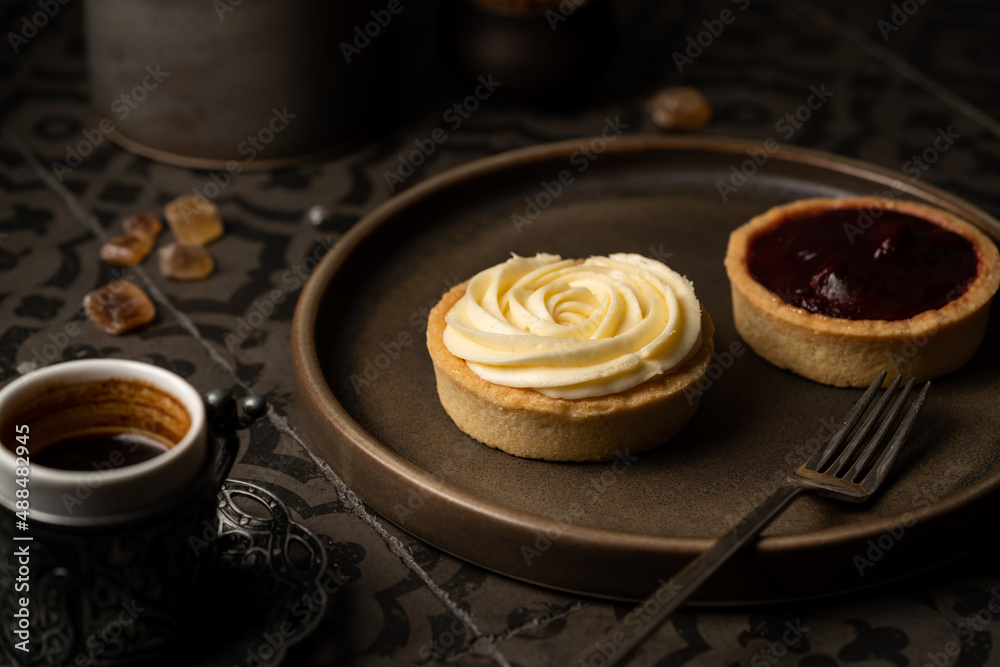 Mini tart with whipped cream and lemon sweet dessert on dark tile background