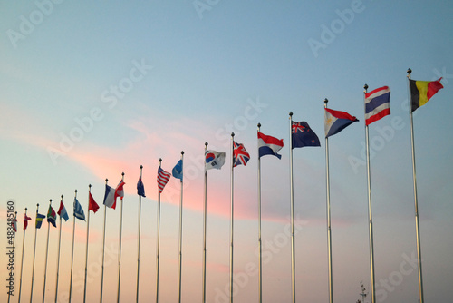 Fotografie The flags of various countries are raised against the backdrop of sunset
