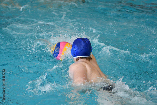 Young men play water polo in an indoor pool 