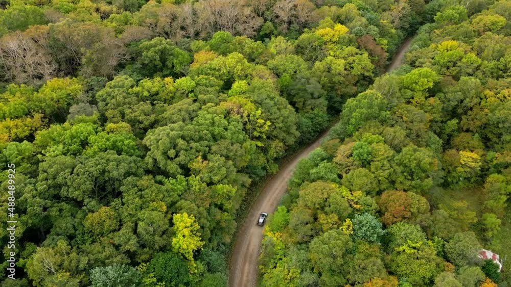 The car drives along a forest road among green trees. View from above. Travel by car in Russia. The car drives along a forest road among green trees. View from above. Travel by car in Russia.