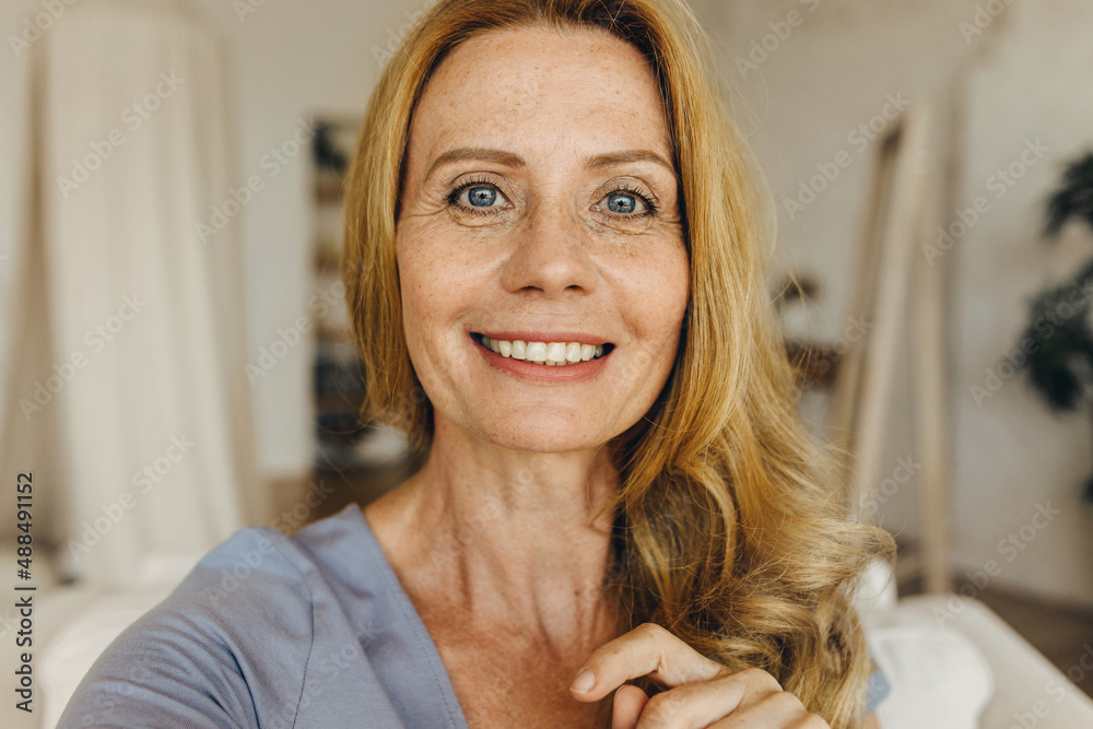 Pretty joyful Caucasian woman of 50s with long waving ginger hair