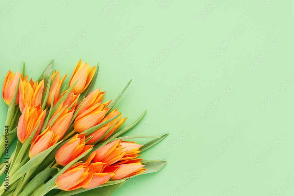 Fototapeta premium Bunch of bright orange tulips on green background. Mother's day, Valentines Day, Birthday c concept