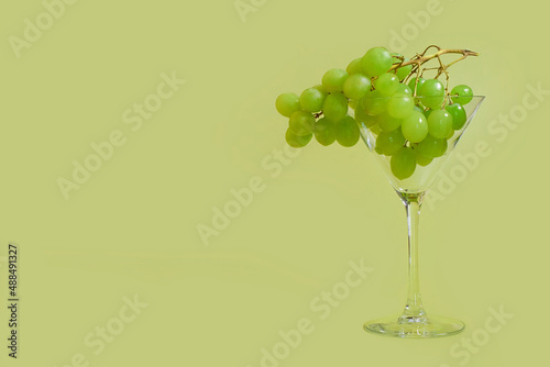 A bunch of green grapes in a martini glass on a colored background