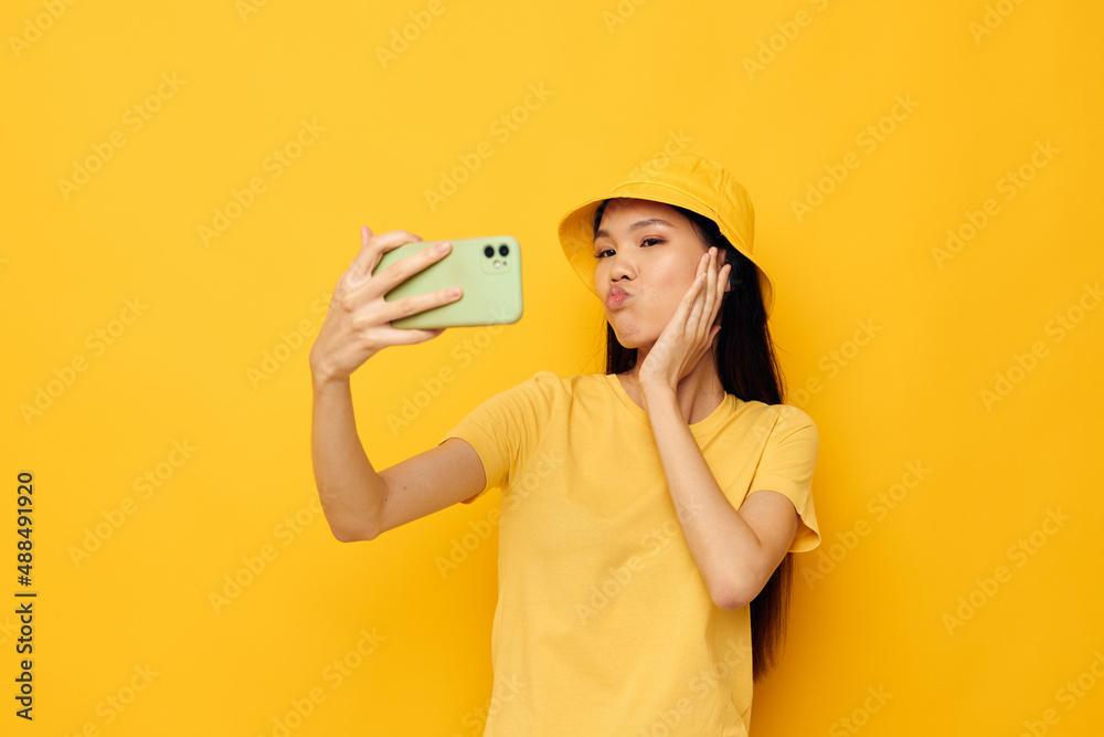 woman with Asian appearance talking on the phone posing fashion yellow background unaltered woman with Asian appearance talking on the phone posing fashion yellow background unaltered
