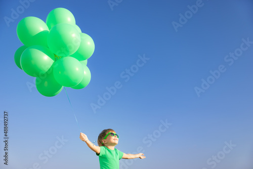 Happy child with green balloons outdoor
