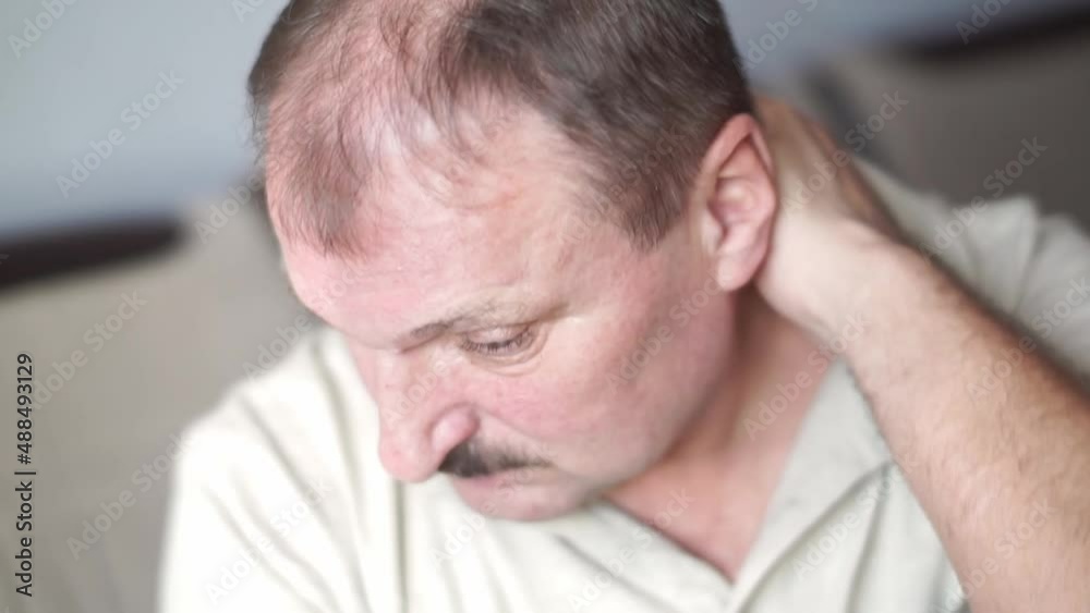 An elderly mustachioed man with bald head rubs and massages neck joints with symptoms of pain in cervical spondylosis, osteoarthritis, stenosis, muscle spasms. Concept of healthcare, medicine products An elderly mustachioed man with bald head rubs and massages neck joints with symptoms of pain in cervical spondylosis, osteoarthritis, stenosis, muscle spasms. Concept of healthcare, medicine products