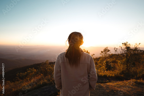 Silhouette woman looking at beautiful mountain valley in fog at sunrise in summer, Travel and tourism. © oatawa