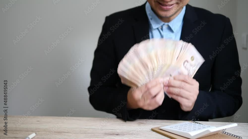 Thai businessman is happily holding Thai Baht banknote
