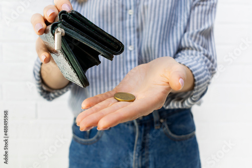 Close-up of a young womans hands pours the last coin out of an open wallet. No money, bankruptcy, financial problems, crisis, unemployment, lack of funds to pay expenses concept.