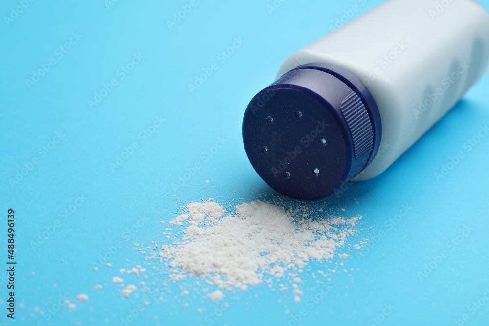 Bottle and scattered dusting powder on light blue background. Baby cosmetic product Bottle and scattered dusting powder on light blue background. Baby cosmetic product